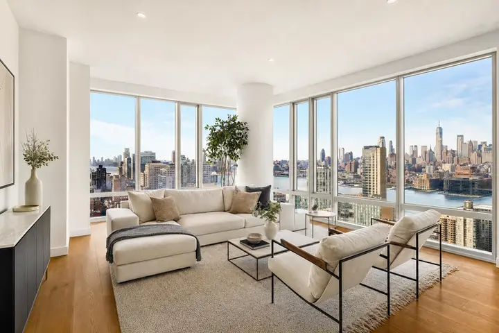 Stylish living room with floor-to-ceiling windows offering a stunning Manhattan skyline view over the river.