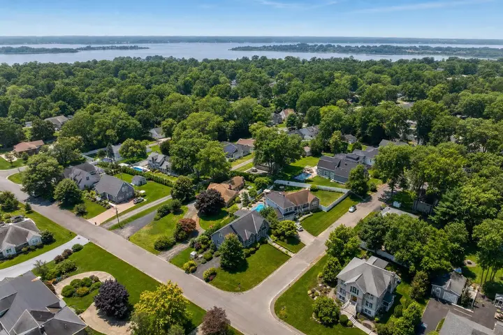 Aerial view of a suburban neighborhood with tree-lined streets, houses, and a river in the background, showcasing drone photography NJ.