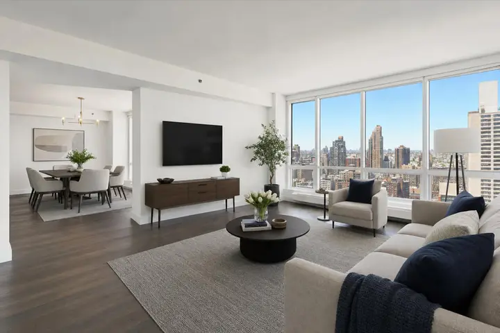 Modern living room with NYC skyline view, featuring a cozy seating area, wall-mounted TV, and elegant dining setup.