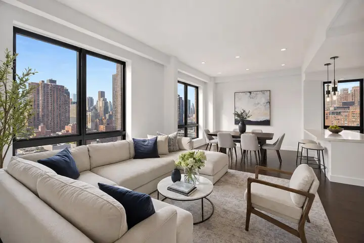 Spacious NYC apartment living room with modern decor, large windows showcasing city skyline, and elegant dining area.