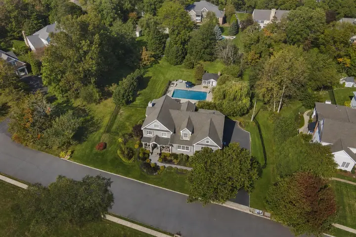 Aerial drone view of a suburban New Jersey neighborhood with rows of houses, green lawns, and tree-lined streets