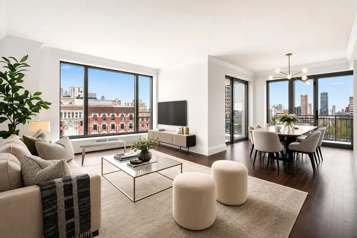 Open-concept living and dining area in a modern apartment with large windows showcasing a cityscape view.