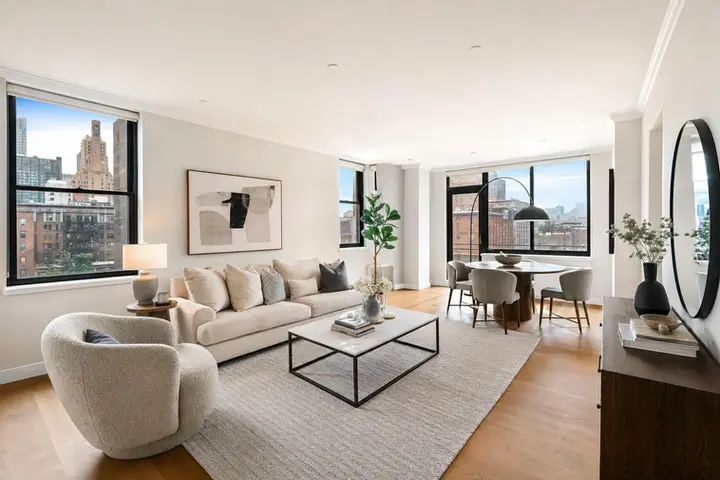 Stylish living and dining area with modern furniture, natural lighting, and NYC skyline views through large windows.