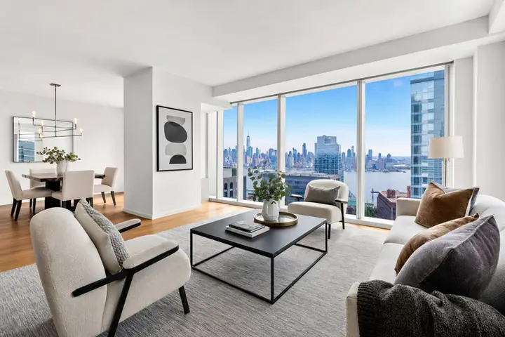 Modern living room with elegant furnishings and large windows offering a breathtaking NYC skyline view.