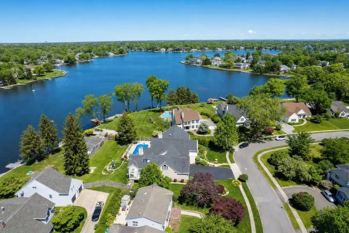 Aerial drone view of a modern suburban home with manicured lawn and surrounding neighborhood in New Jersey