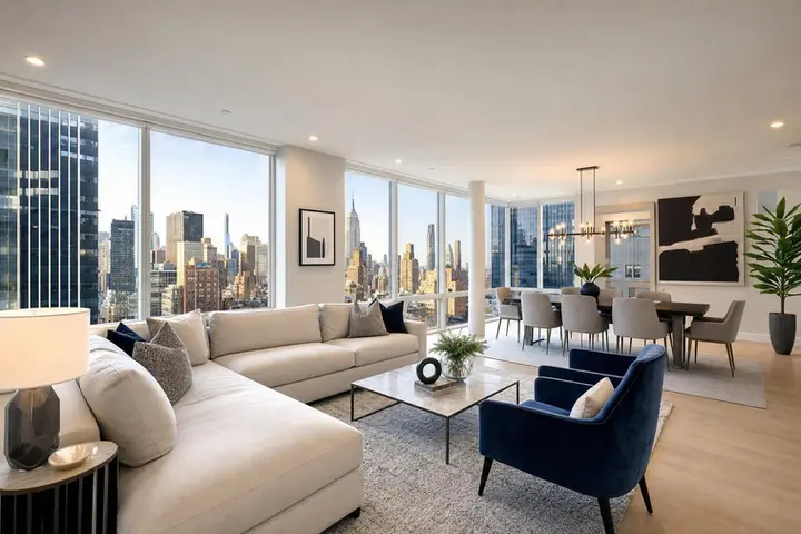Spacious modern living and dining area with city skyline views, featuring a white sofa, blue armchair, and stylish decor.