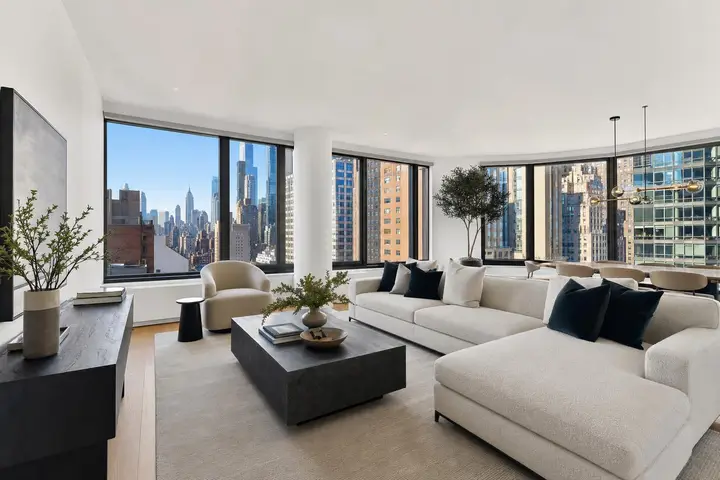 Stylish NYC apartment interior with modern furniture, large windows, and city skyline views.
