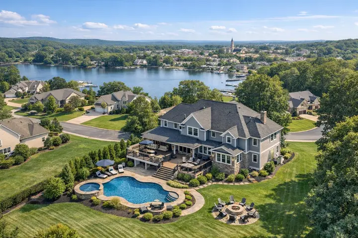 Large suburban house with a pool and patio overlooking a lake, captured from above, showcasing drone photography NJ.