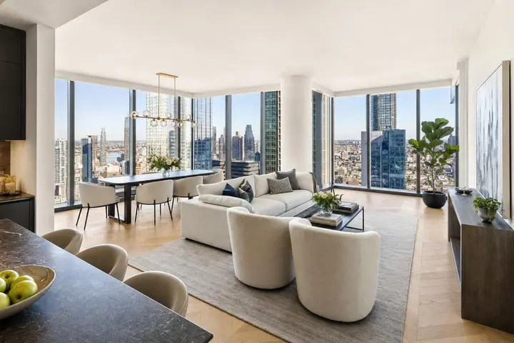 Modern living and dining space with panoramic NYC skyline views through floor-to-ceiling windows.