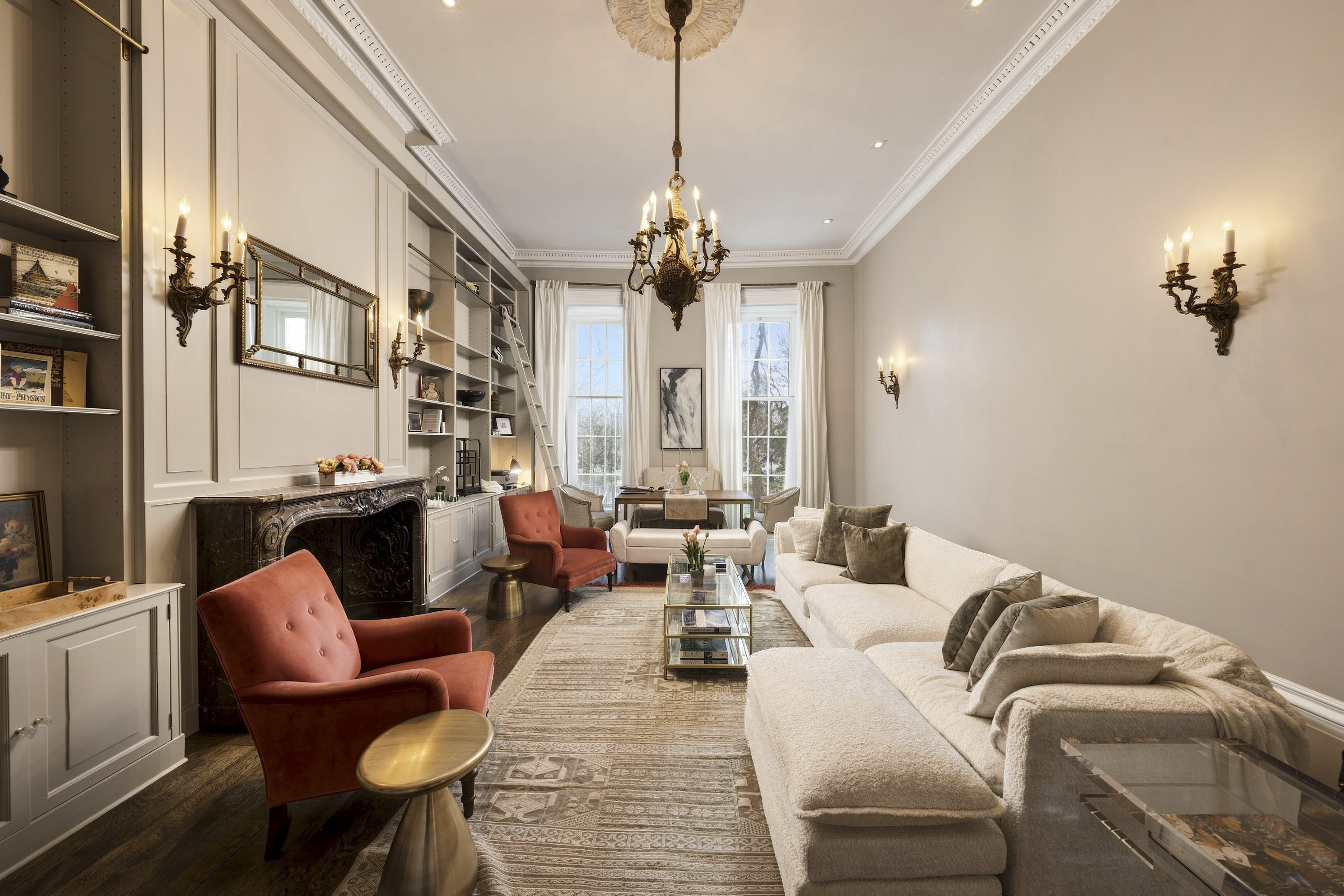Elegant NYC townhouse living room with ornate ceiling medallion, marble fireplace, built-in shelving and tall windows — architectural photo