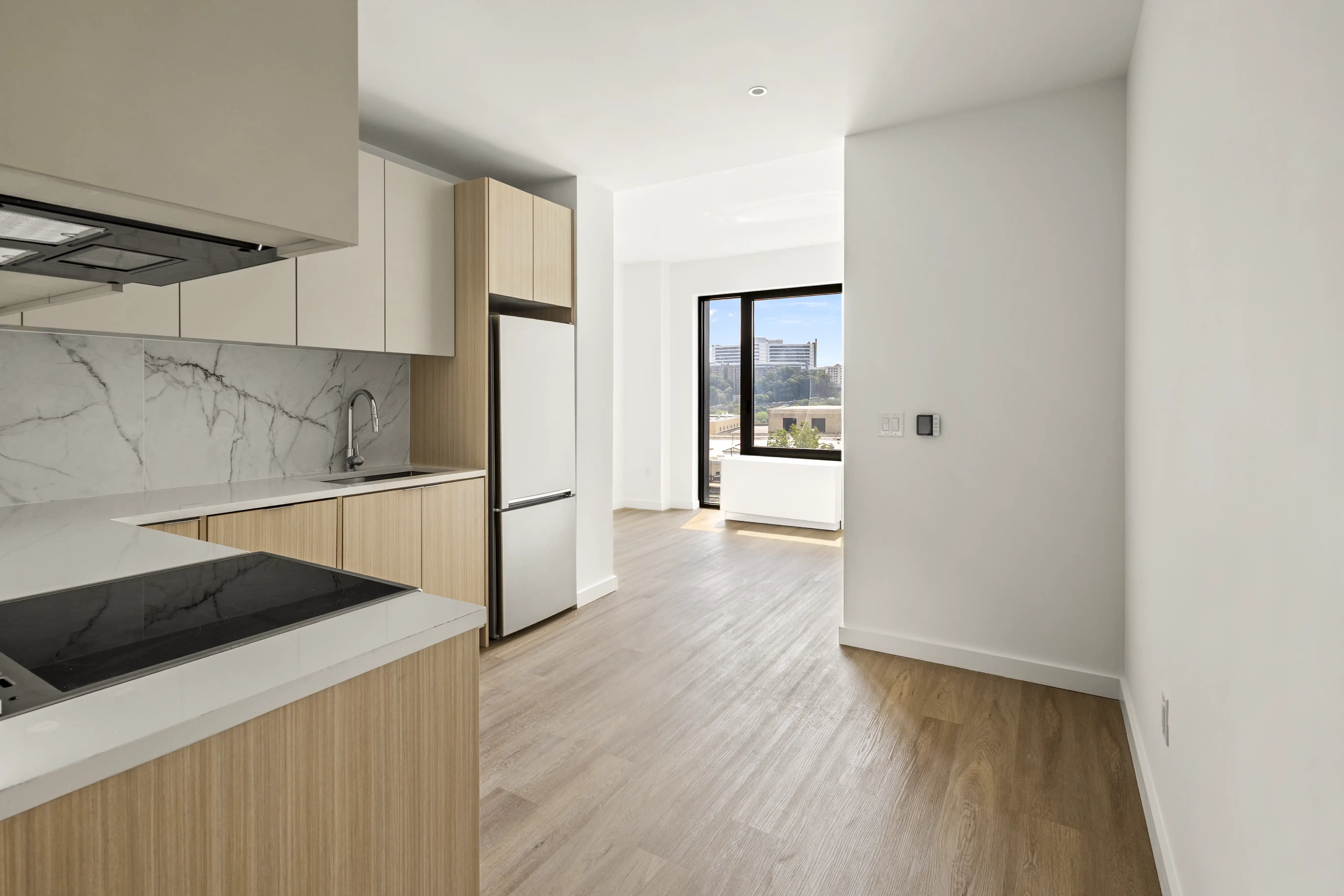 Queens condo interior — modern kitchen with light wood cabinetry and bright open living space